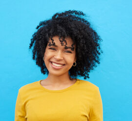 Cropped shot of a young woman looking happy while posing against a blue wall